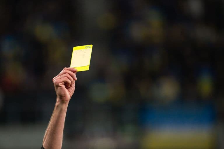 A referee shows a yellow card in the Premier League